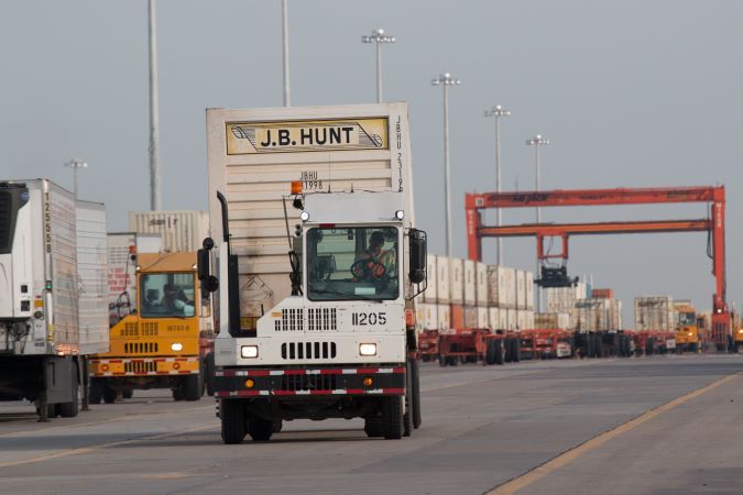 A hostler vehicle moves a freight container within the facility.