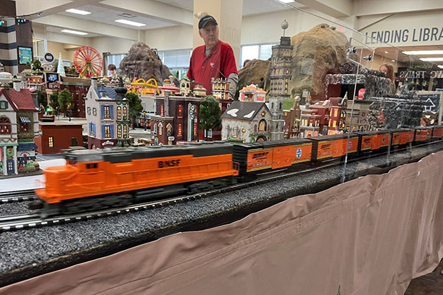 Model BNSF train zooming past the miniature Christmas town