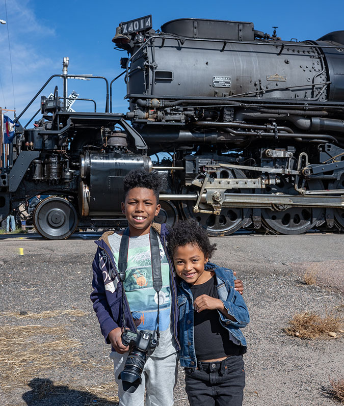 Daecian and his sister Kate standing in front of a steam locomotive.